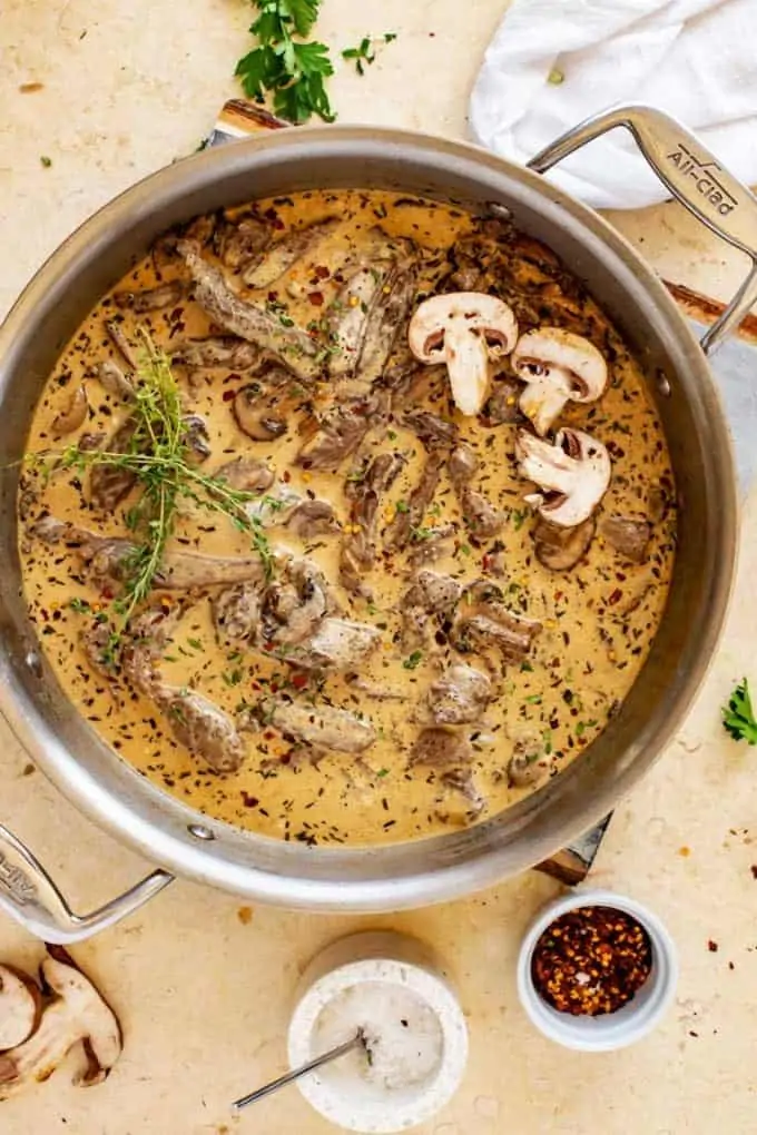 Overhead photo of a large skilled of Keto Beef Stroganoff garnished with fresh thyme and mushrooms.