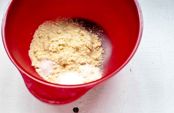 Photo of a red bowl with almond flour, baking powder, salt, and xanthan gum.