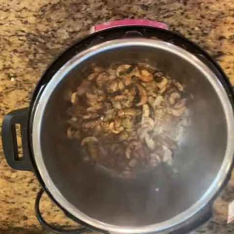 Overhead photo of mushrooms, onions, and thyme in an Instant Pot.