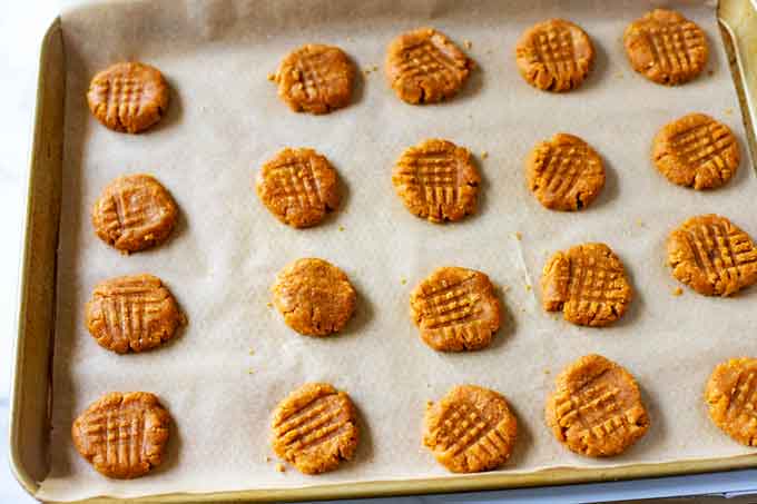 Photo of flourless peanut butter cookies on a parchment lined cookie sheet.