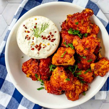 Square overhead photo of BBQ Cauliflower Wings on a white plate with a small dish of ranch dressing beside it.