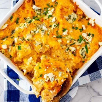Square overhead photo of Keto Buffalo Chicken Casserole in a white casserole dish sitting on a blue and white napkin garnished with parsley.