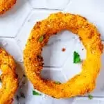 Close up square photo of a Keto Onion Ring on a white tile background.