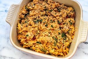 Photo of a casserole dish with shredded chicken, bacon, and chopped spinach tossed with a creamy ranch BBQ Sauce.