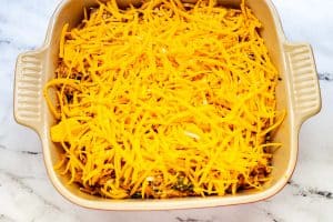 Photo of a square casserole dish with a casserole covered in cheese.