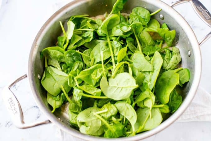 Photo of fresh unwilted spinach in a large skillet.