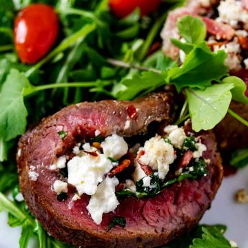 Close up photo of stuffed flank steak on a bead of greens.