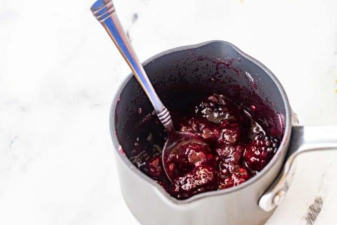 Photo of a blackberry sauce in a small saucepan.