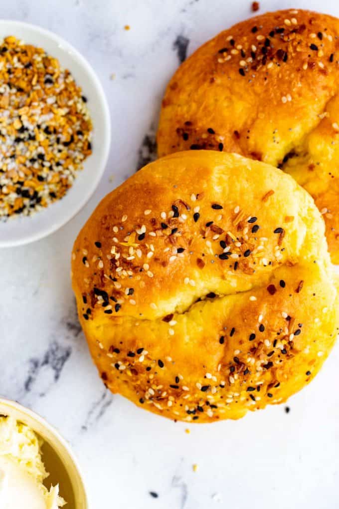 Photo of keto fathead bagels on a white background with a small dish of everything seasoning next to it.