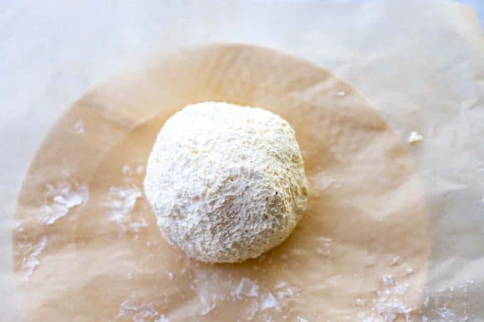 Photo of a cheese ball on a sheet of parchment paper.