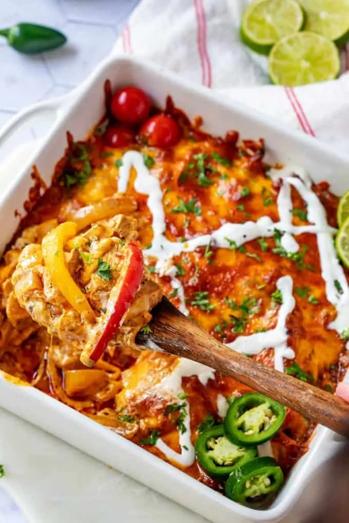 Photo of a white casserole dish with Keto Fajita Casserole being scooped from it with a wooden spoon.