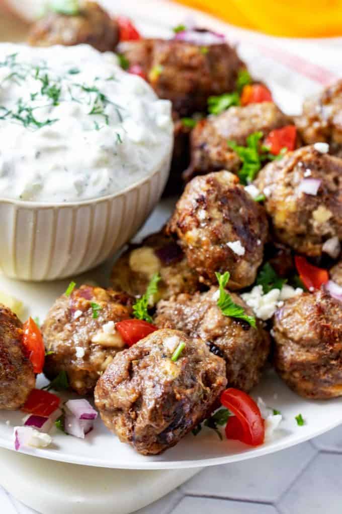 Close up photo of a plate of keto lamb meatballs garnished with feta, red onion, and parsley.