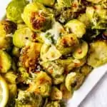 Square photo of a white platter full of cheesy Instant Pot Brussels Sprouts.