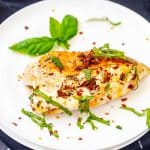 Square photo of a white plate with Keto Cream Cheese Chicken garnished with basil.