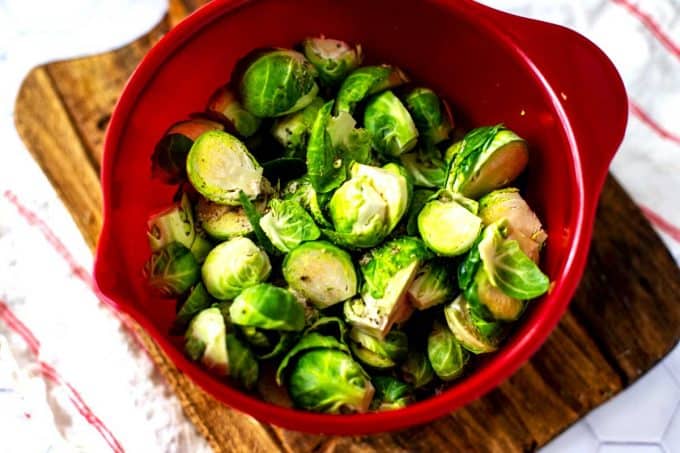 Photo of a red bowl with seasoned Brussels Sprouts.