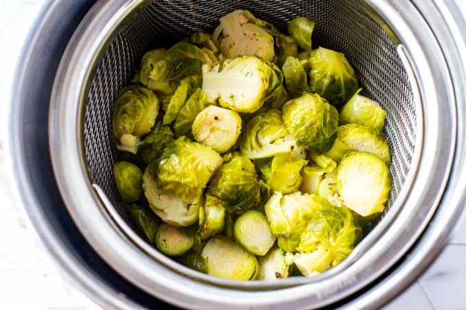 Photo of cooked Brussels Sprouts in a steamer basket inserted into a Pressure Cooker.