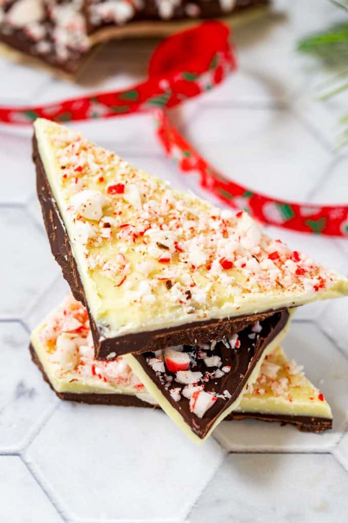 Close of photo of three stacked pieces of sugar free peppermint bark on a white background with a Christmas ribbon behind it.