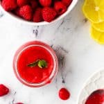 Square photo of Photo of a small jar of keto raspberry sauce garnished with mint with a bowl of raspberry sauce.