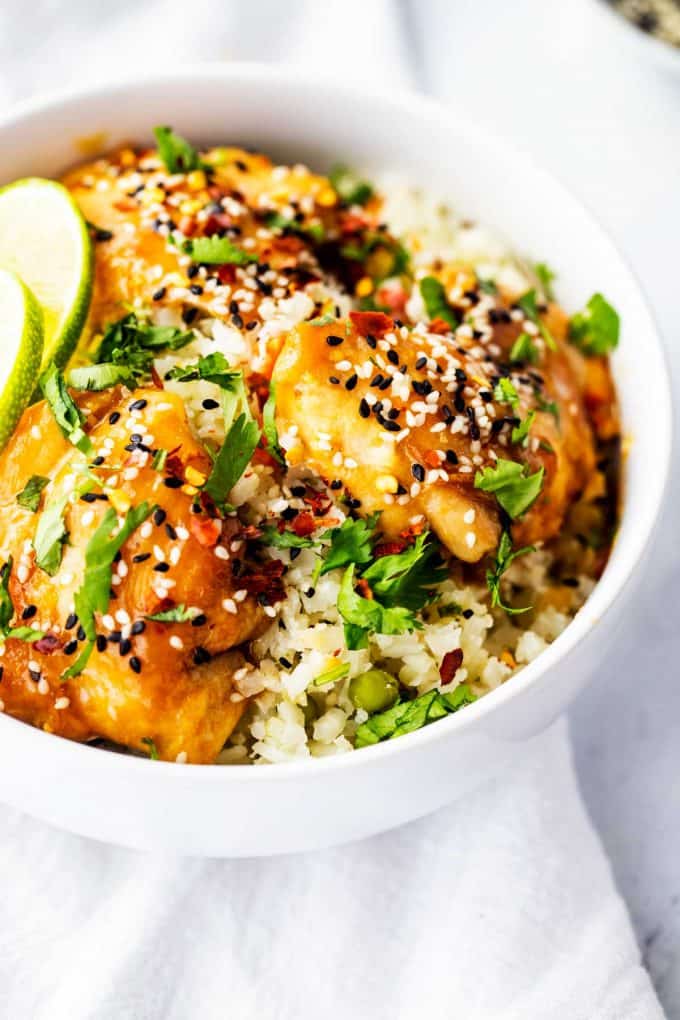 Three-quarters overhead photo of Keto Sesame Chicken garnished with sesame seeds, cilantro and lime.