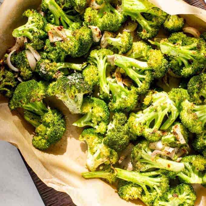 Roasted broccoli on a parchment lined baking sheet.