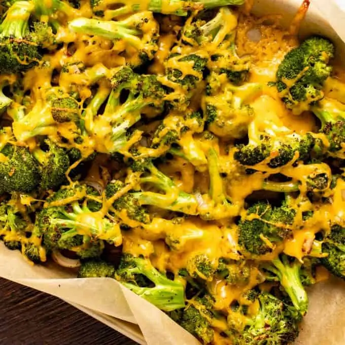 A parchment lined baking sheet with cheesy roasted broccoli.