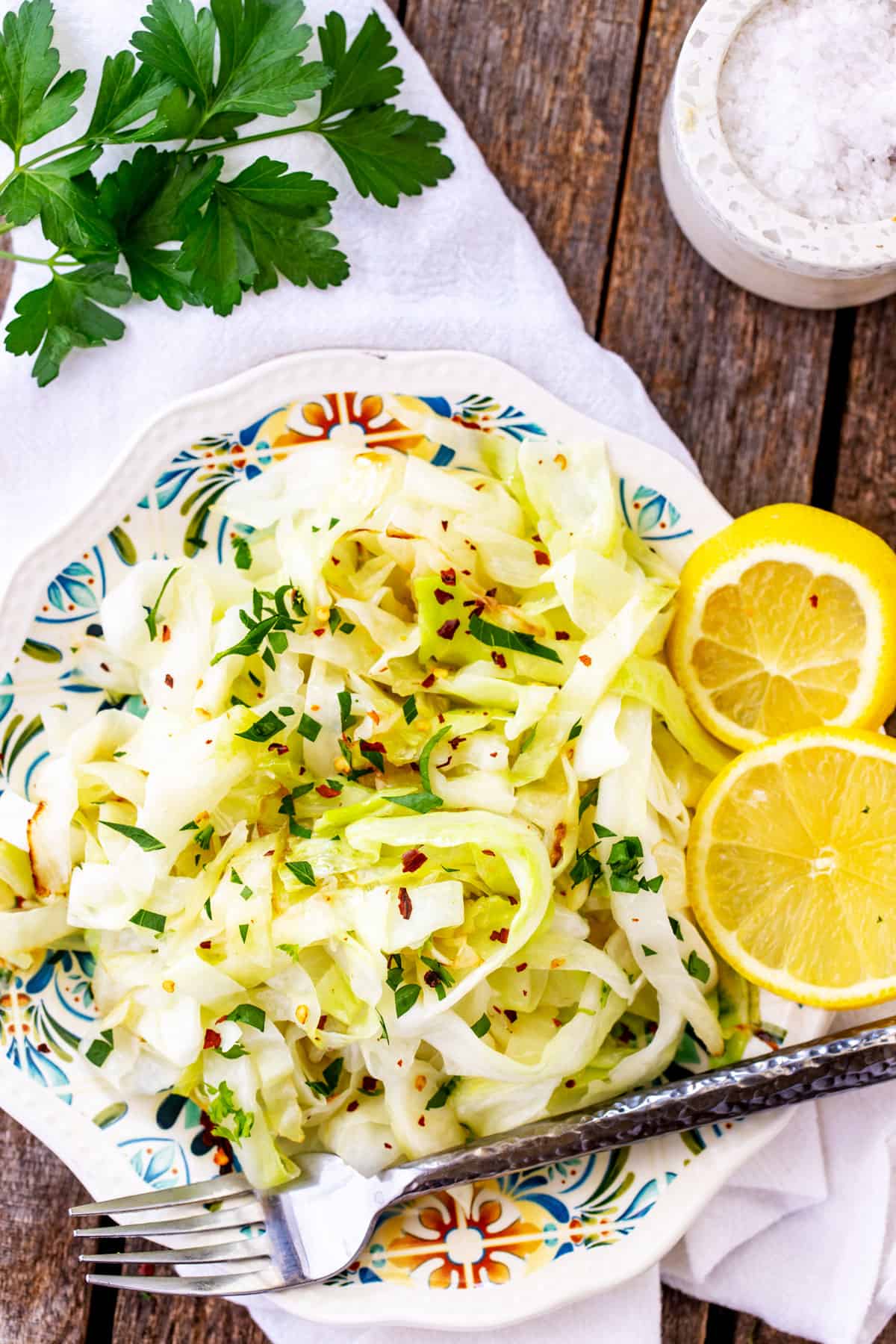 Overhead photo of a plate of cabbage noodles garnished with lemon and parsley.