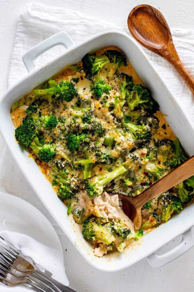 Photo of a keto chicken broccoli casserole with a spoon taking a serving out of the white casserole dish.