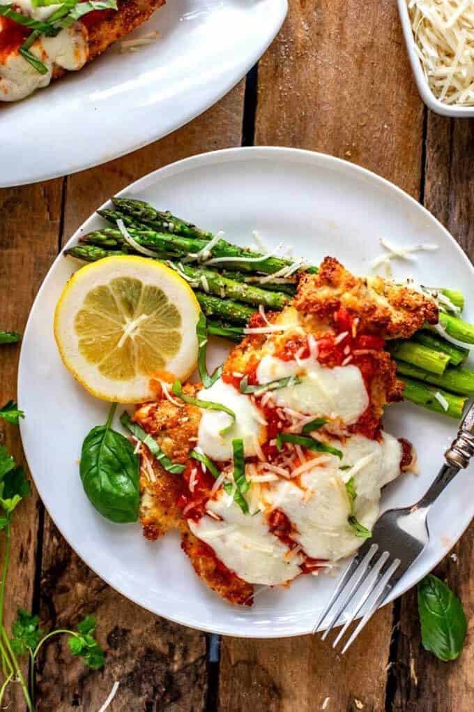 Overhead photo of keto chicken parmesan on a white plate against a dark wooden background.