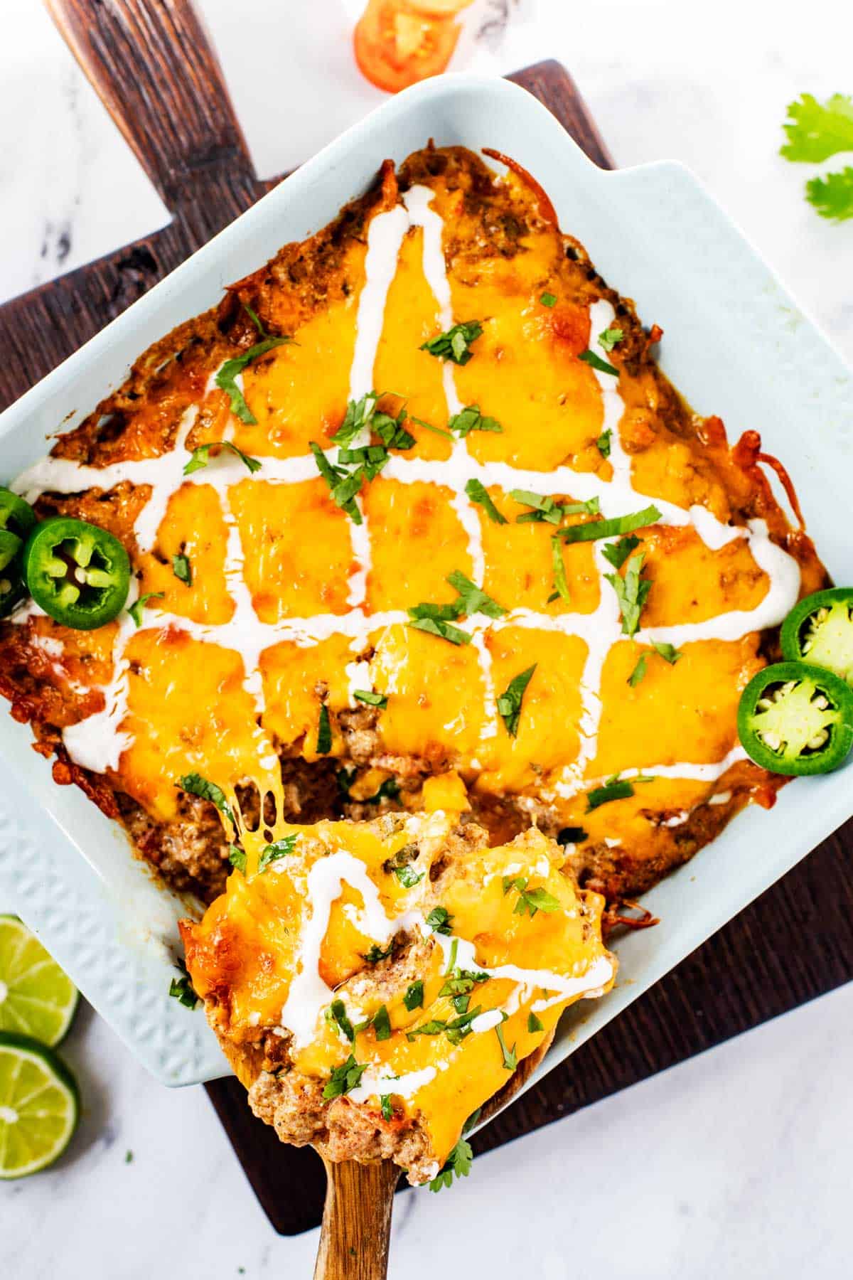 Photo of a light blue square casserole dish with Keto Taco Casserole with a spoon in it.