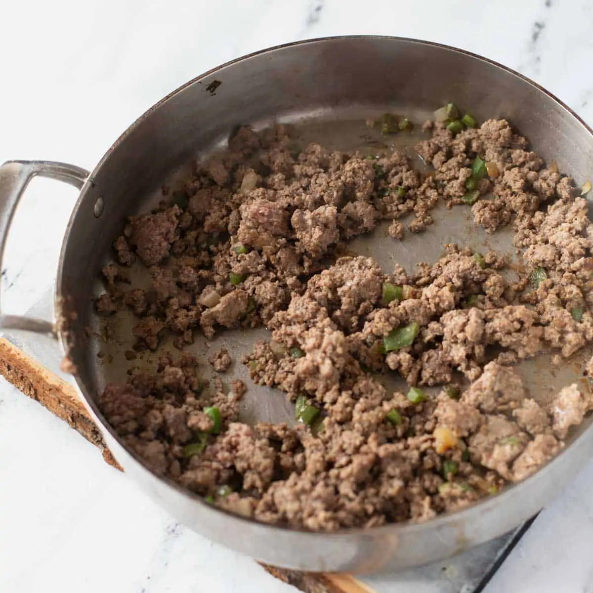 Photo of ground beef, onion and jalapeno in a skillet.