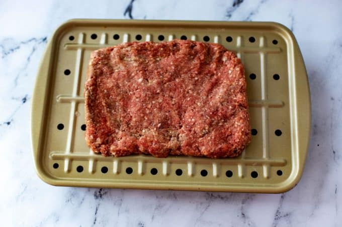 Photo of meat for a meatloaf shaped into a rectangle in a pan.