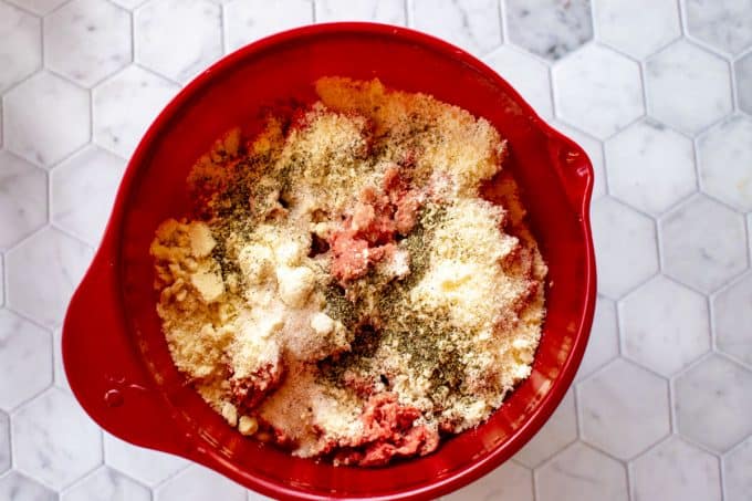 Photo of meat, seasonings, almond flour, and parmesan cheese in a bowl.