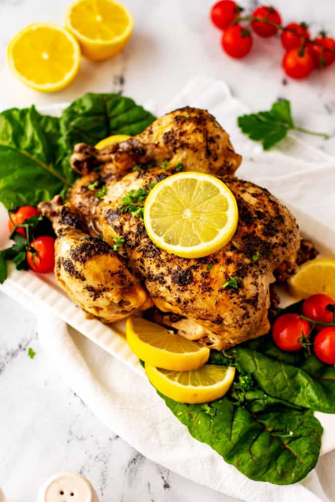 Photo of a white platter with Instant Pot Frozen Whole Chicken with a lemon on it.
