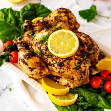 Photo of a white platter with Instant Pot Frozen Whole Chicken with a lemon on it.