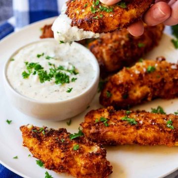 Photo of a keto chicken tender being dipped into ranch dressing.