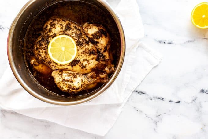 Instant pot with a whole cooked chicken in it.