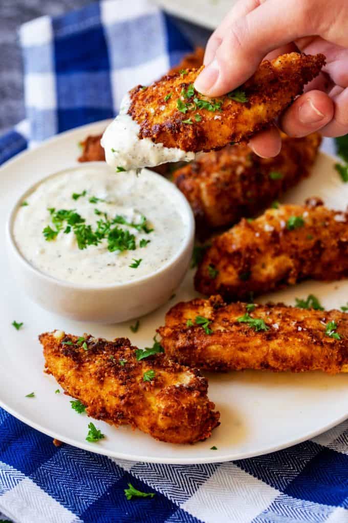 Photo of a keto chicken tender being dipped into ranch dressing.