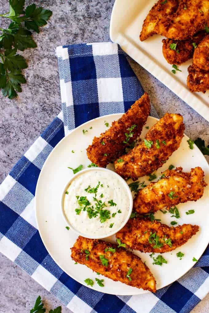 Overhead photo of a plate of keto chicken tenders with a platter full of them sitting behind it.