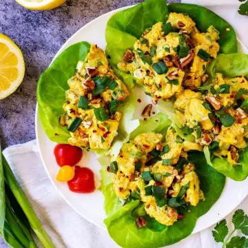 Overhead square photo of Keto Curry Chicken Salad in lettuce cups on a white plate.