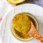 Square photo of a spoon resting on top of a small glass jar with keto poppy seed dressing.