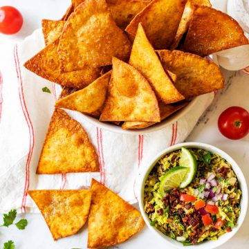 Square Overhead photo of a bowl of low carb tortilla chips with a few chips scattered below and a small bowl of guacamole.