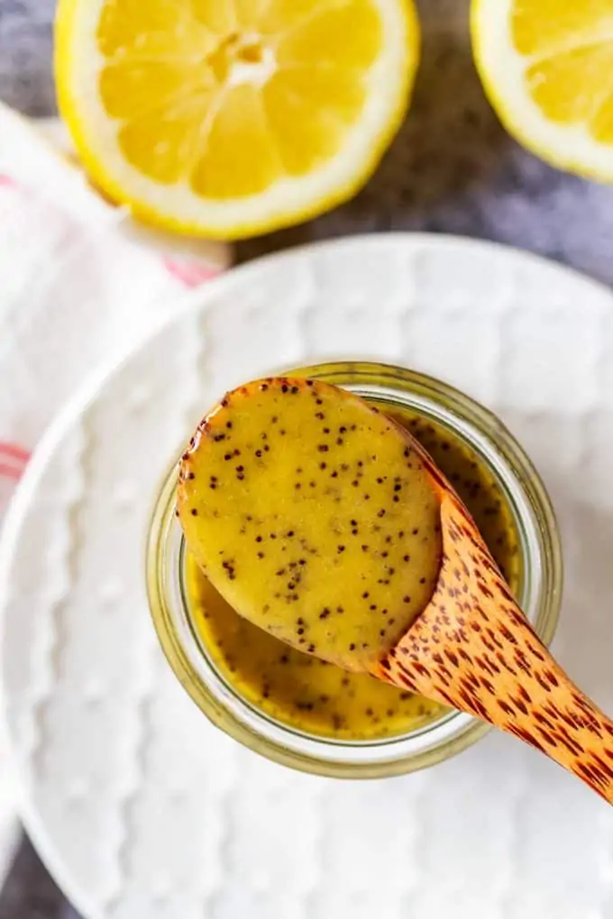 Overhead photo of a spoon resting on top of a small glass jar with keto poppy seed dressing.