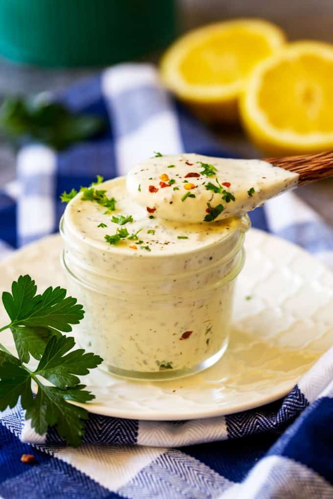 Photo of a wooden spoon with keto ranch dressing resting on a small jar.