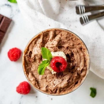 Square overhead photo of keto chocolate pudding garnished with whipped cream, a raspberry, and mint.