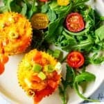Close up overhead square photo of quinoa egg muffins on a plate next to salad greens.