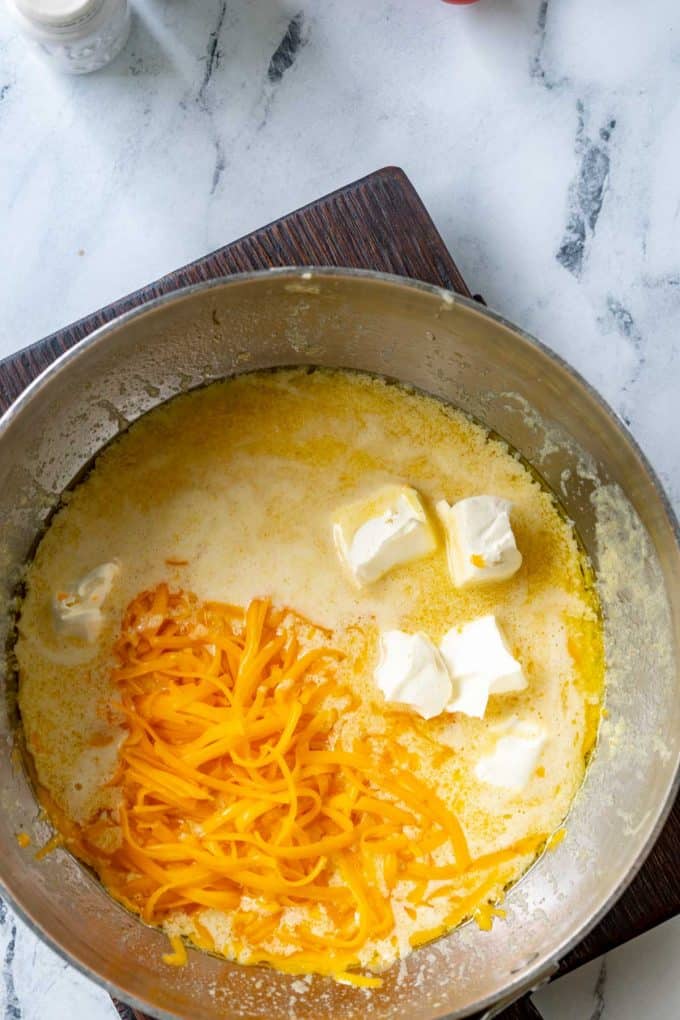 Overhead photo of a skillet with melted butter, seasonings, cheddar cheese, and cream cheese.