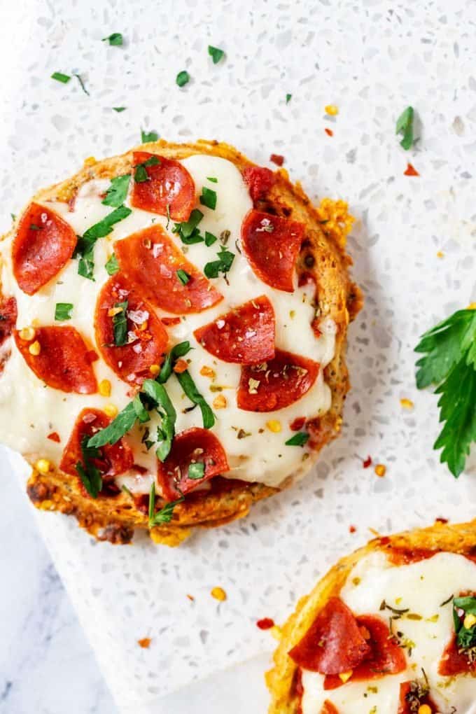 Overhead photo of a pizza chaffle on a white background with a part of another keto pizza chaffle next to it.