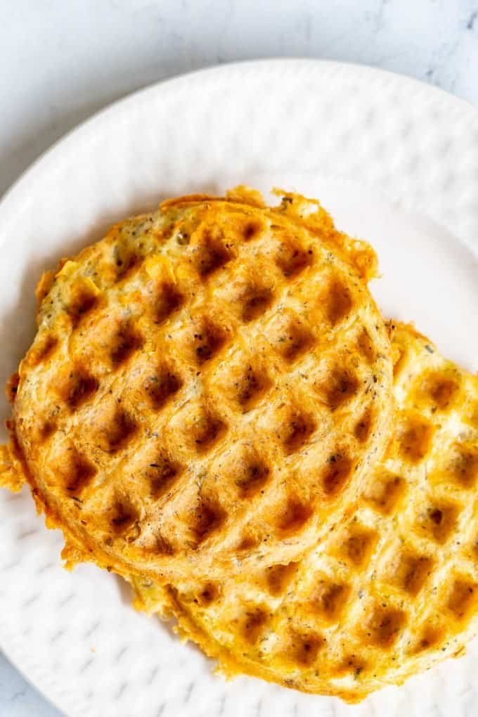 Twos prepared chaffles with Italian seasonings on a white plate.