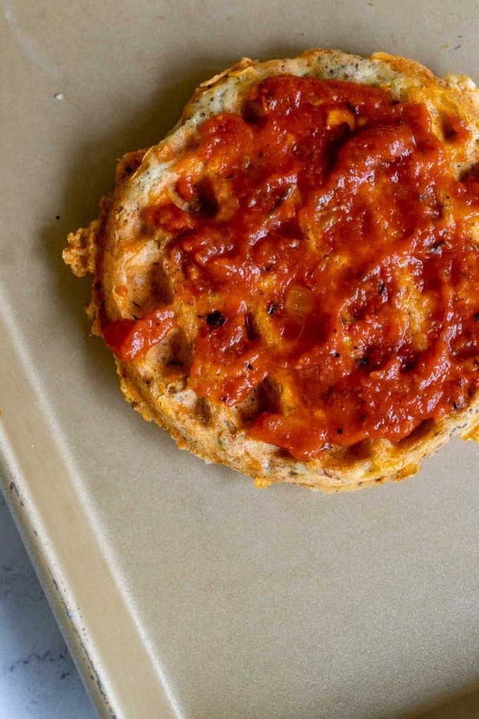 Photo of a baking sheet with a chaffle covered in marinara.