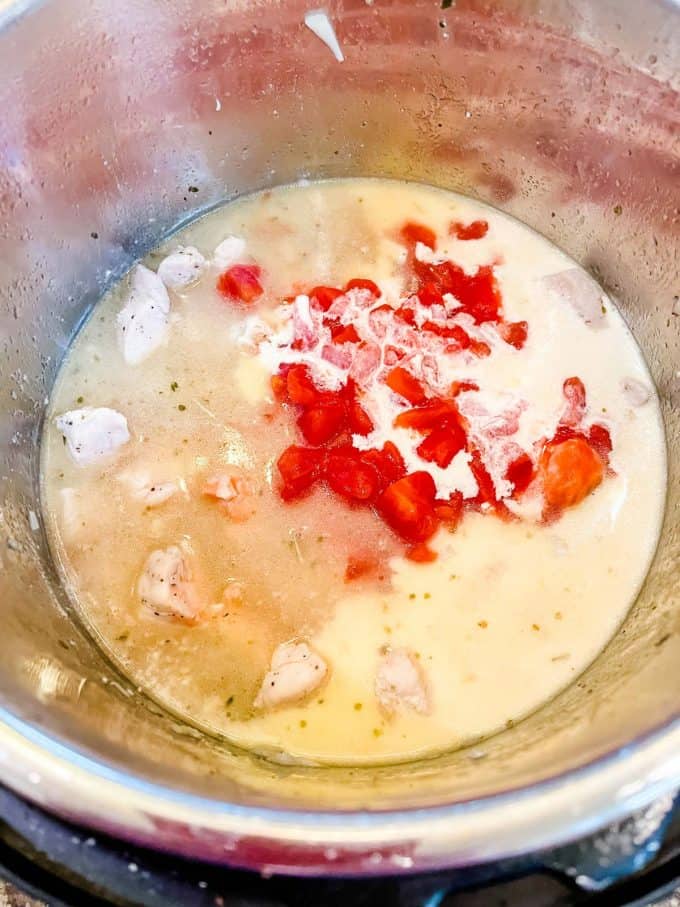 Photo of cream and tomatoes being added to instant pot chicken spaghetti.